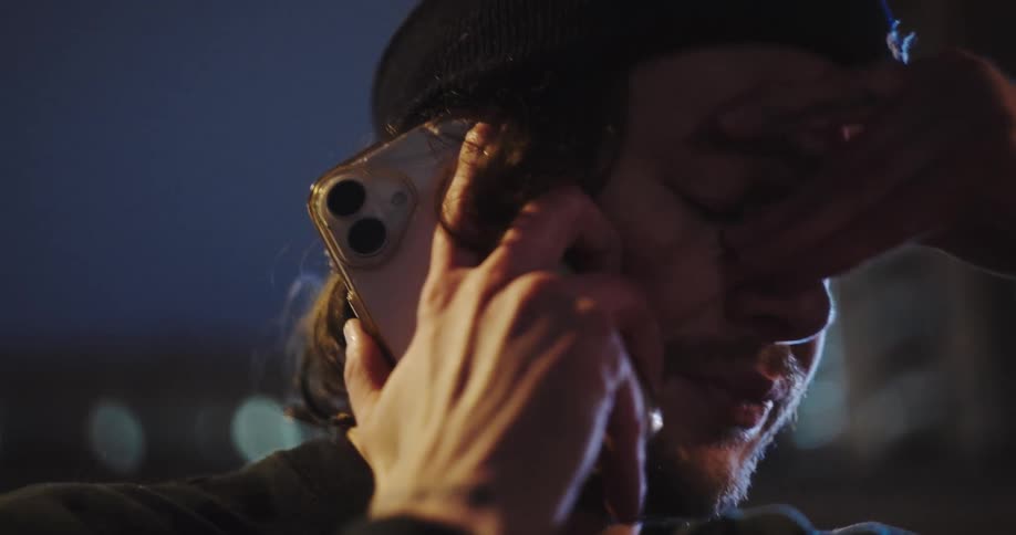An emotional close-up of a crying man receiving bad news on a phone call at night