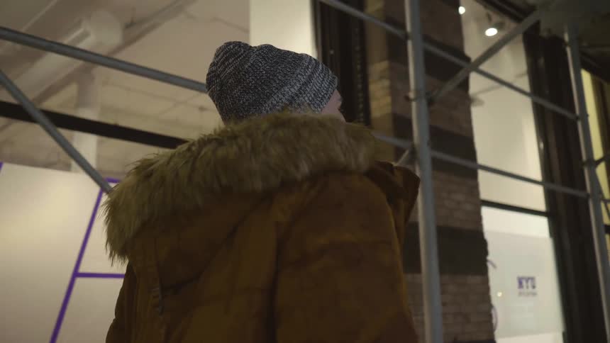 A man wears a heavy coat while walking on a city sidewalk