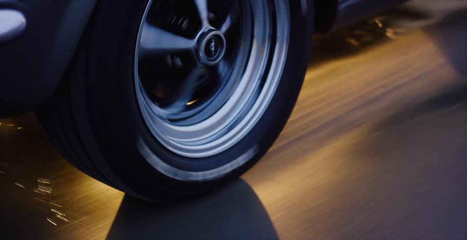 A dramatic seamless loop shows a classic Ford Mustang wheel spinning at high speed on a reflective surface, creating sparks