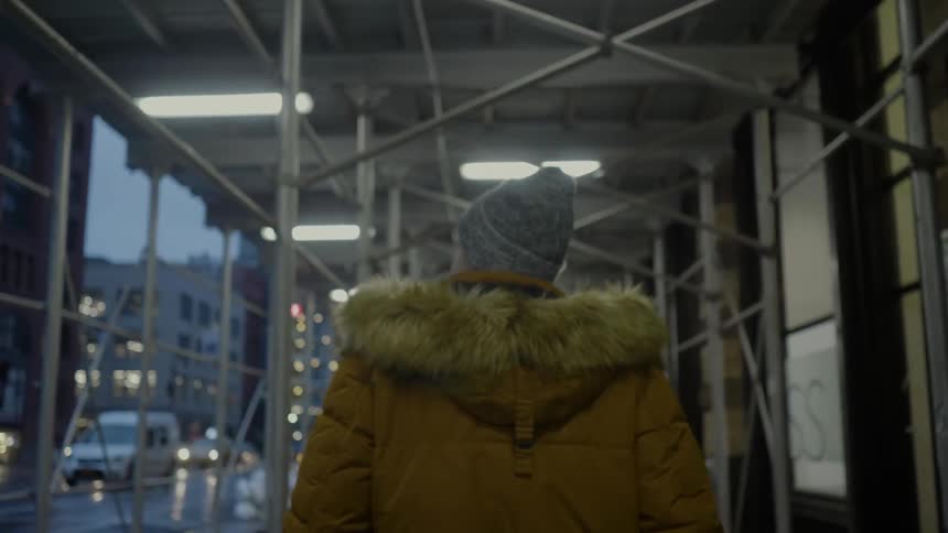 A man is walking under a railing by a building