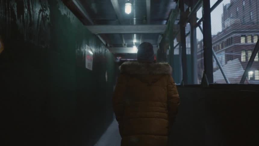 A man wears a heavy coat while walking in a city