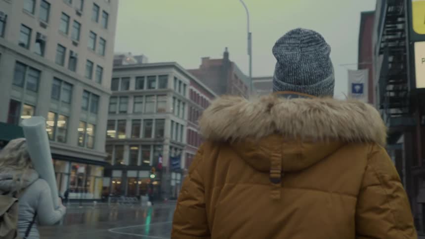 Pedestrians walk on a city sidewalk on a rainy day