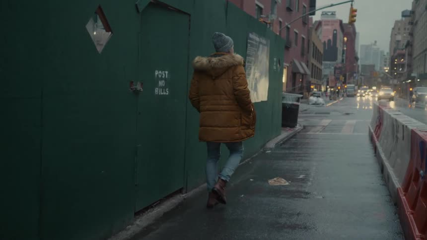 A man walks down a city sidewalk on a stormy day