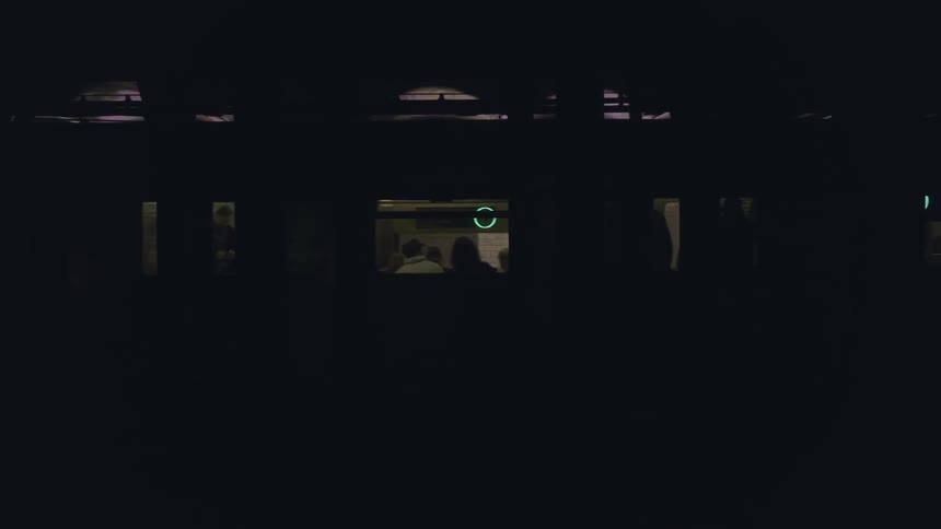 Passengers ride a subway train at night