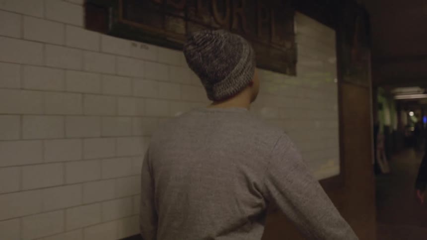 A man wearing a winter hat walks in a subway station