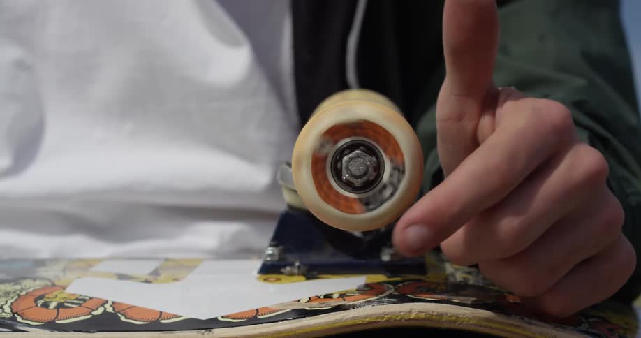 A hand stops a spinning skateboard wheel