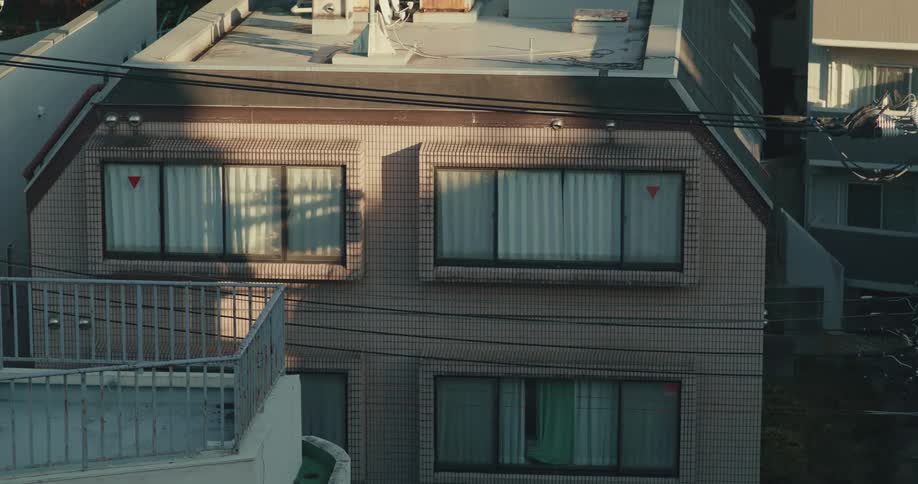 The facade of a tiled residential building in a Japanese suburb on a sunny day