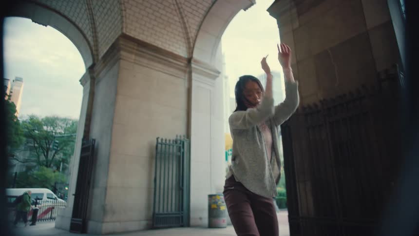 An expressive dancer gracefully performs a contemporary routine under a grand stone archway in the city in slow motion