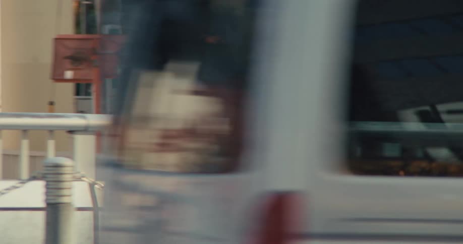 Slow motion side view of a young Japanese businessman with a backpack walking across a city bridge during his morning commute
