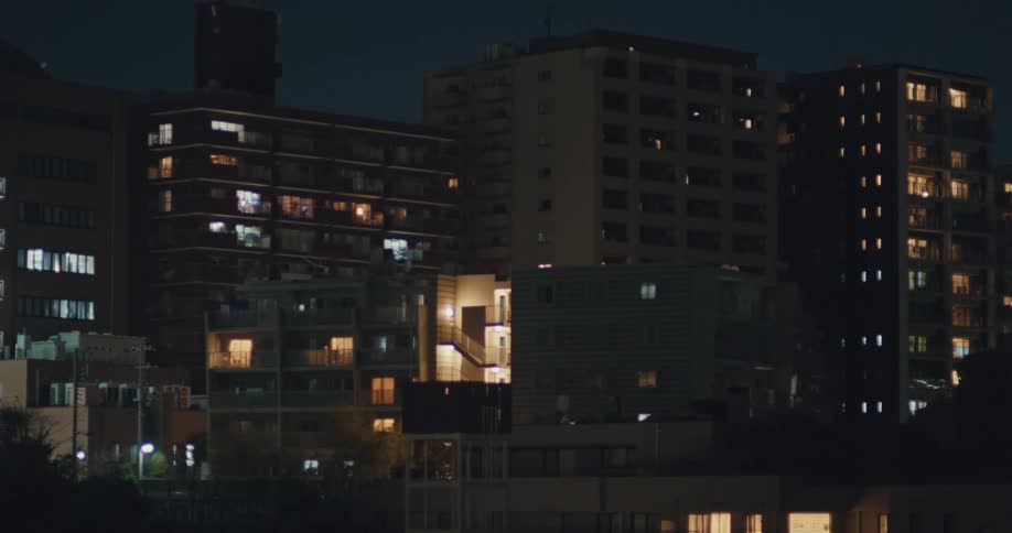 Late-night view of residential apartment buildings with illuminated windows in a quiet city
