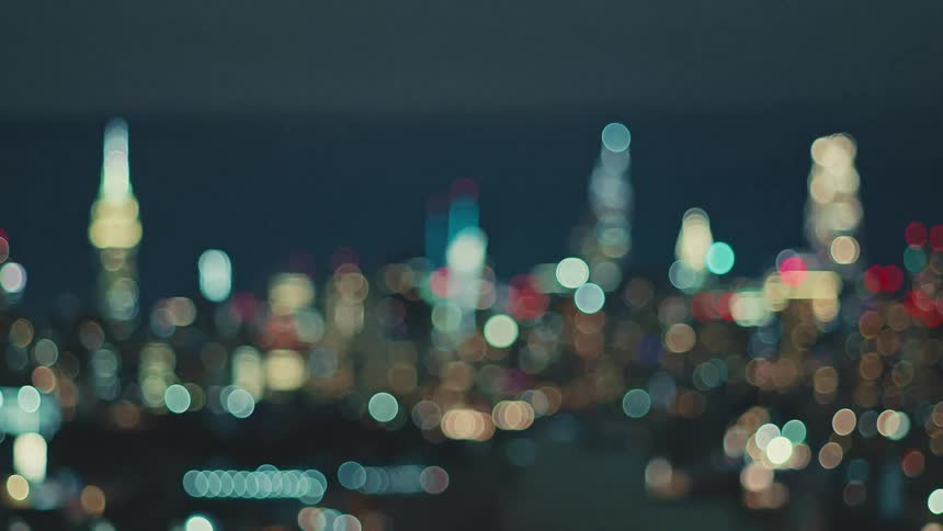 The vibrant New York City skyline blurs into a dreamy bokeh of colorful lights at night