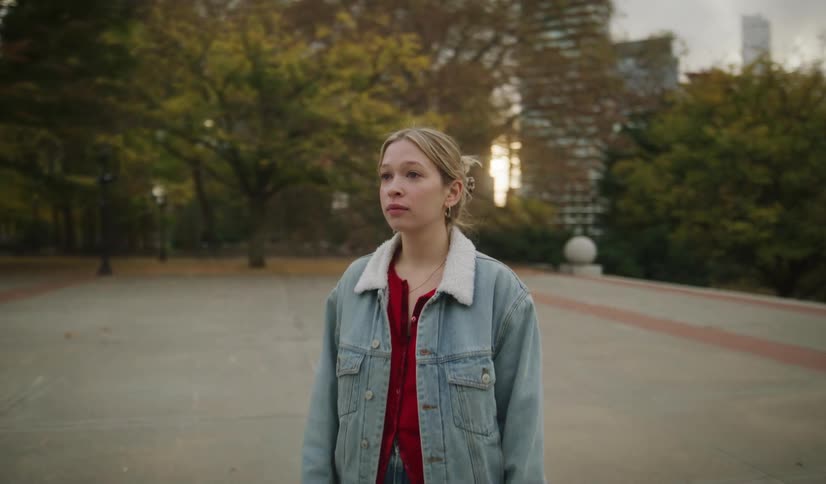 A young woman and child stroll through an autumn city park before the woman turns to walk pensively toward the camera in slow motion