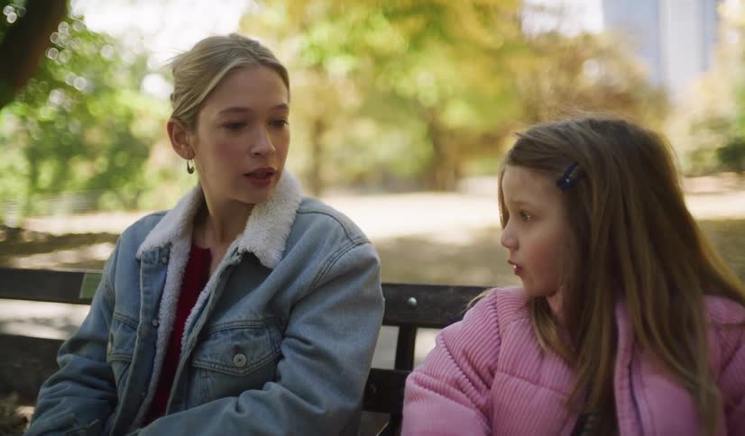 A close-up of a young woman and a little girl having an intimate and caring conversation on a park bench on a sunny autumn day