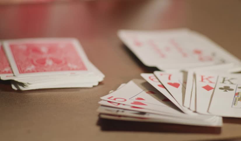 A person lays down a hand of playing cards onto a table during a card game