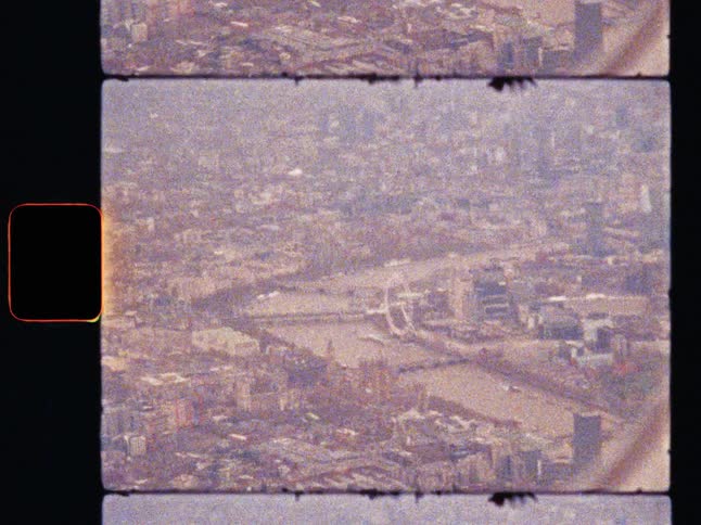 Vintage Super 8 film aerials over the hazy London cityscape, revealing the River Thames, the London Eye, the Palace of Westminster, Big Ben and Houses of Parliament