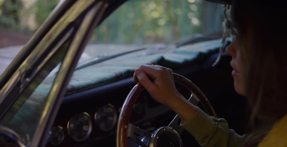 Slow motion close-up of a woman's hand tapping on the vintage wooden steering wheel of her car