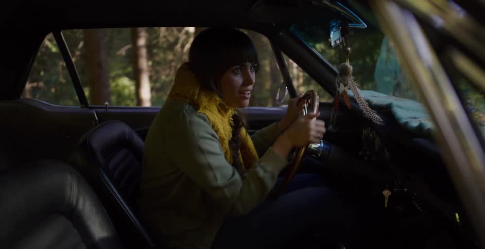 A young woman in a classic car becomes terrified while stopped on a remote road in the woods