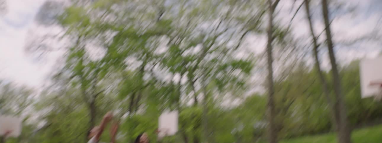 Slow motion shot of a basketball player making a basket during a friendly game at a park