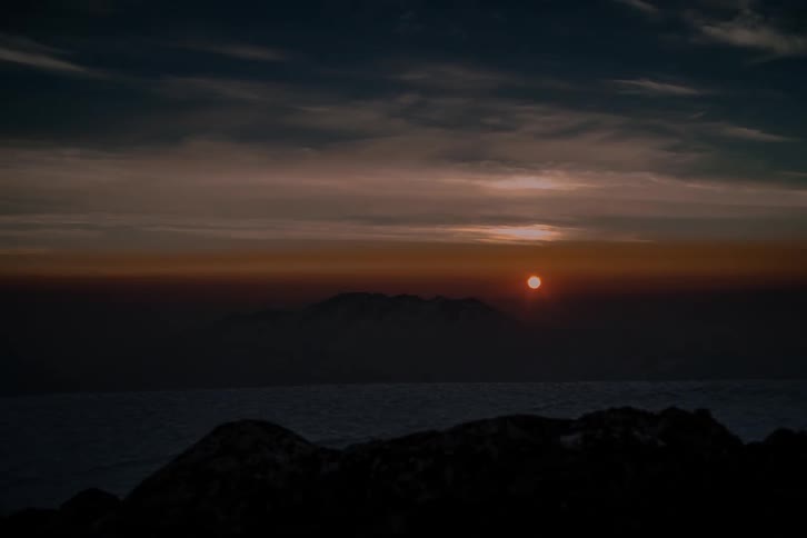 A stunning time-lapse shows the sun rising over a distant mountain range, casting a warm glow across a sea of clouds below