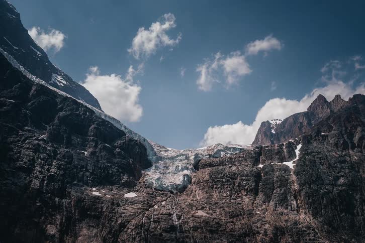 A stunning timelapse of clouds and sunlight moving across a massive glacier nestled in the rugged, rocky mountains