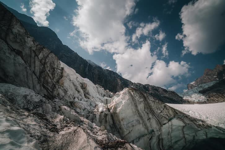 A dramatic time-lapse captures clouds soaring over a vast glacier nestled in the rugged mountains
