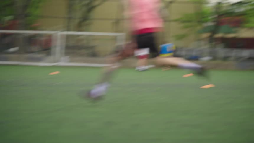 Slow motion footage follows a group of men playing a competitive pickup soccer game on an urban turf field