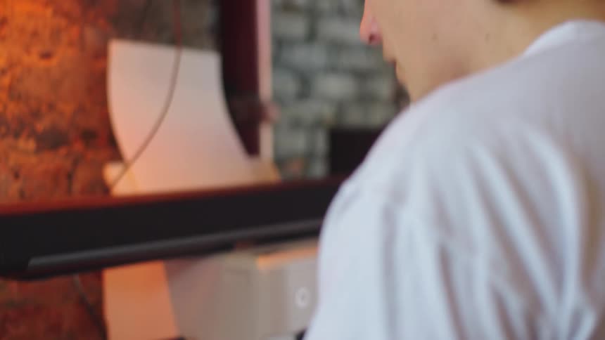 A graphic designer with tattoos and dyed hair works on a creative logo for a football club on his laptop in a home office