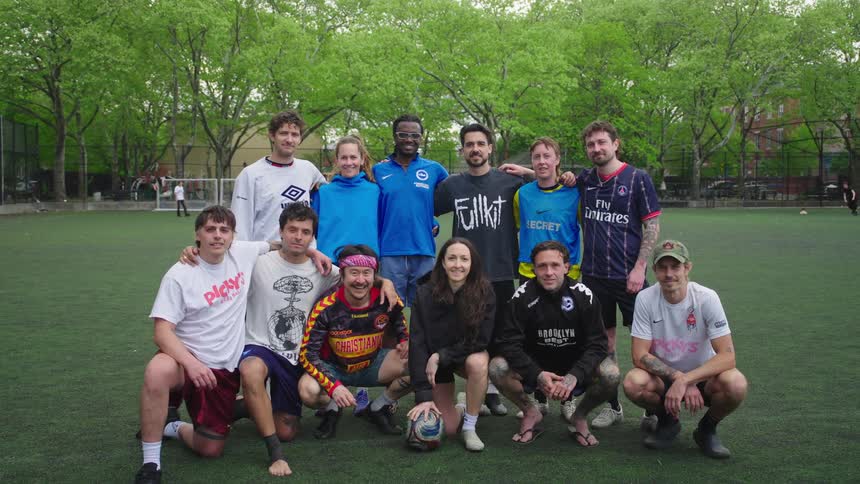 Portrait of a diverse co-ed soccer team smiling for a group photo on an urban astroturf field