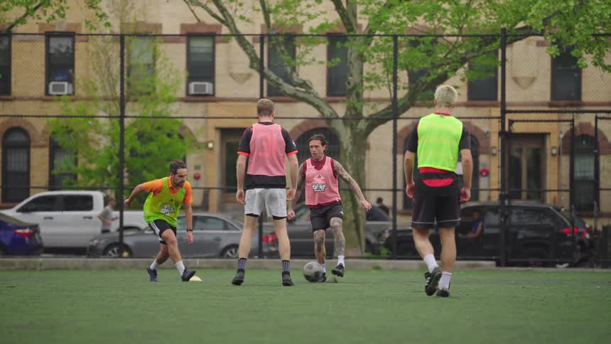 A group of diverse friends play a friendly game of soccer in slow motion on an urban turf field