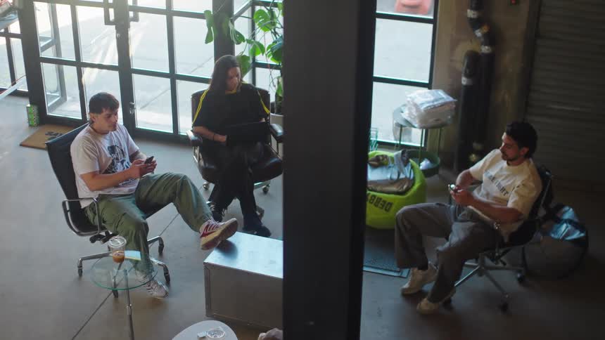 High-angle view of three young colleagues having a casual meeting in a modern industrial office space