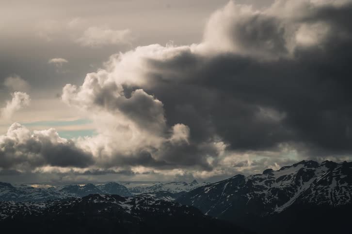 An epic time-lapse of dark, moody clouds moving swiftly over a vast, snow-covered mountain landscape