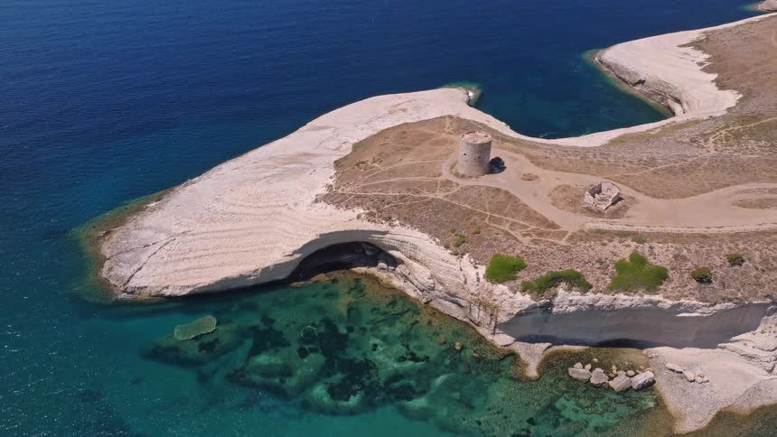 Stunning aerial view of a historic coastal tower on a white limestone peninsula surrounded by clear turquoise waters
