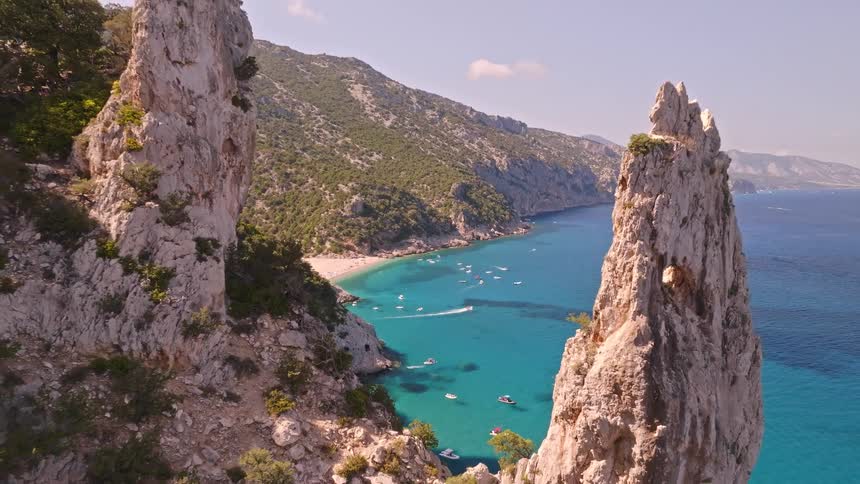 Epic aerial pullback reveals the stunning Cala Goloritzé beach with its turquoise sea and dramatic rock formations in Sardinia, Italy