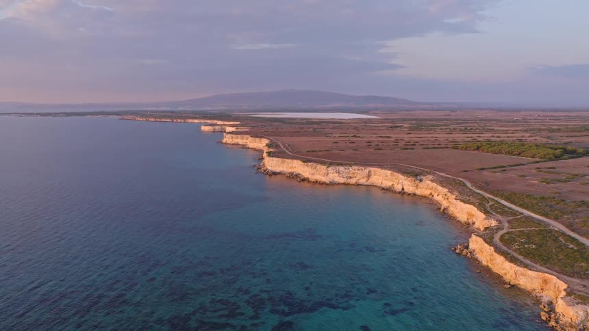 A tranquil aerial view of a stunning coastline with white cliffs and turquoise waters bathed in the soft light of sunset
