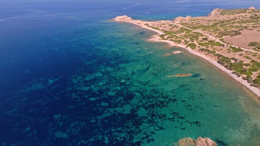 Stunning aerial shot rises to reveal a beautiful, untouched coastline with crystal-clear turquoise and deep blue ocean waters
