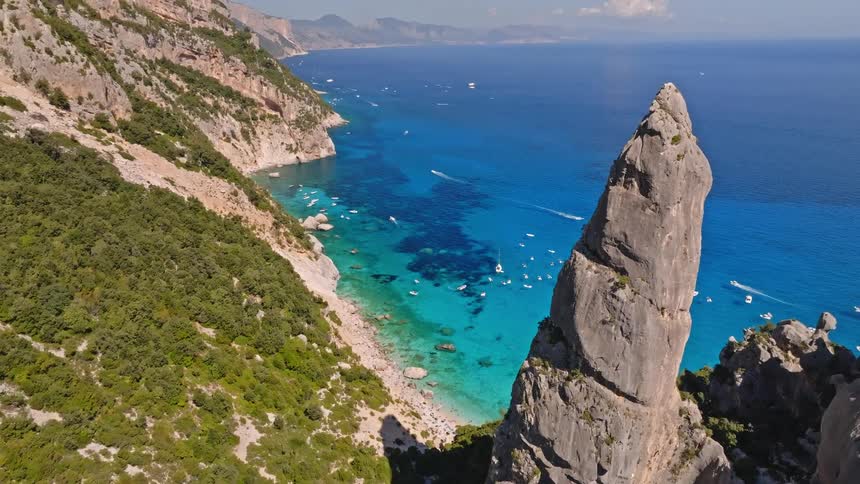 A breathtaking aerial view reveals the famous Aguglia rock spire and the crystal-clear turquoise waters of Cala Goloritzè beach on the coast of Sardinia, Italy
