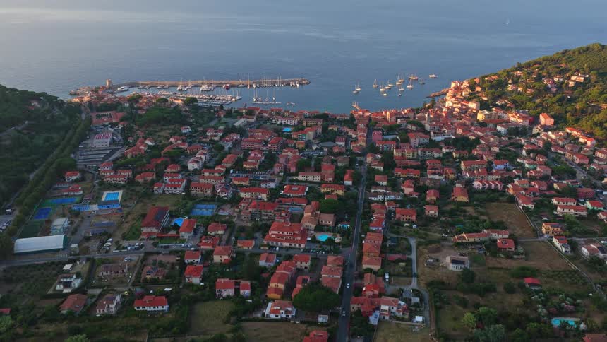 An aerial drone flies slowly over the picturesque Italian coastal town of Marciana Marina on the island of Elba at sunrise