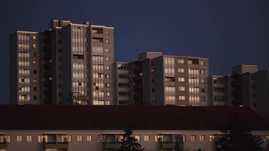 Static view of urban high-rise apartment blocks with lit windows at dusk