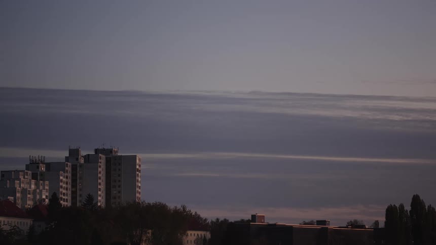A tranquil view of a city skyline with apartment buildings under a calm, cloudy sky at dusk