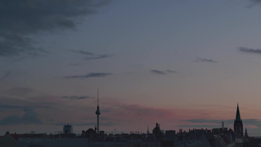 The Berlin city skyline with the iconic TV tower stands calmly against a colorful sunset sky