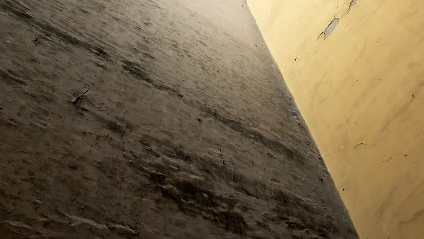 An abstract low angle shot of two old, weathered walls meeting in the corner of a building