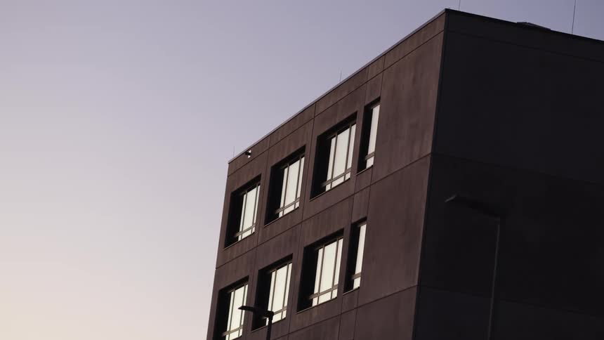 The geometric lines of a modern architectural building stand out against the soft light of a twilight sky