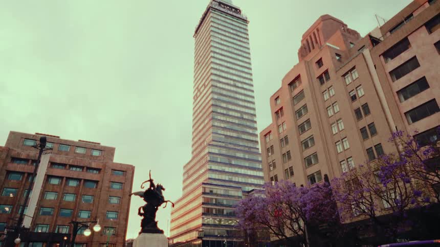 A slow tilt up reveals the iconic Torre Latinoamericana skyscraper in the heart of Mexico City on an overcast day