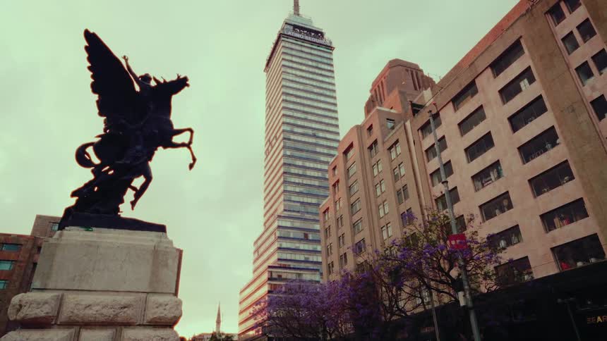 A dramatic low-angle shot of the Torre Latinoamericana skyscraper with a Pegasus statue in the foreground in downtown Mexico City