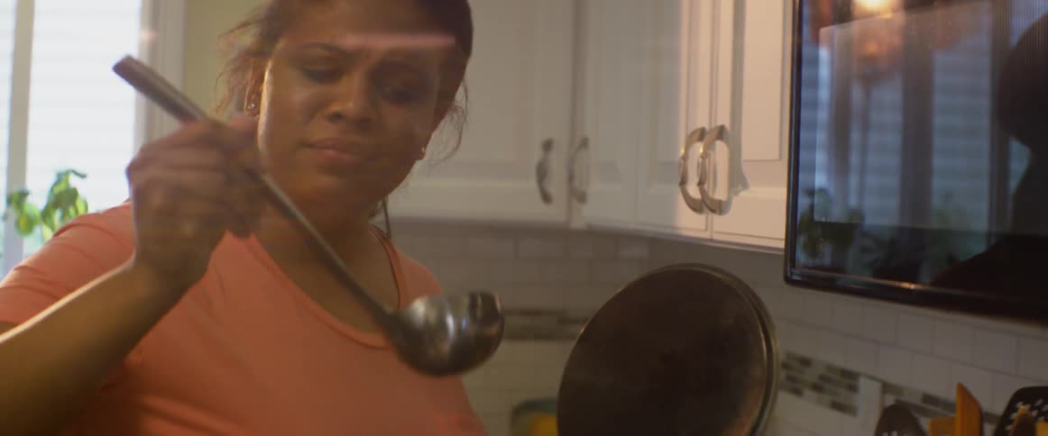 A woman tastes something from a ladle