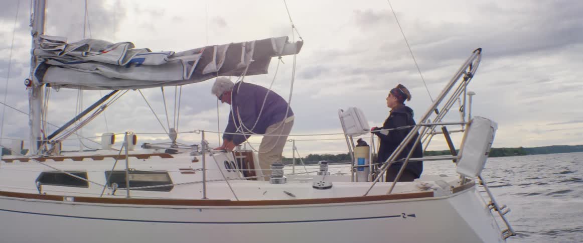 Man ties ropes on sailboat