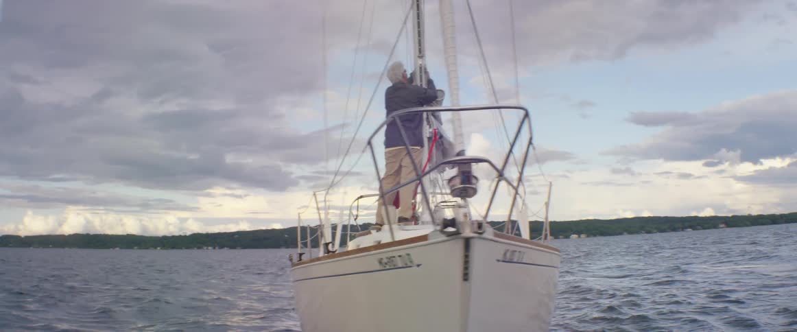 Two people try to raise the sail on a ship