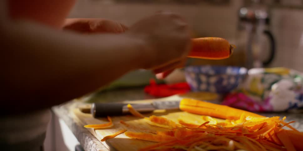 A woman is peeling carrots in a kitchen