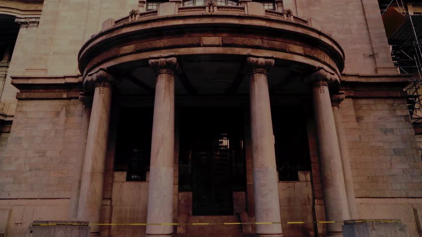 A slow downward tilt from a low angle reveals the grand, columned entrance of the historic Palacio de Bellas Artes in Mexico City