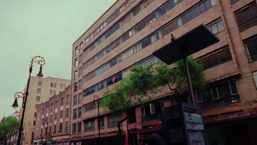 A slow, low-angle tracking shot reveals an aged, multi-story apartment building on a city street